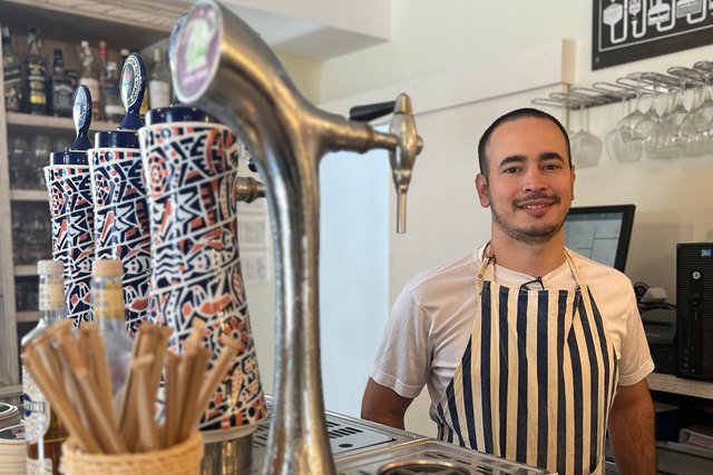 Camilo Jara poses wearing an apron behind the bar at Casa Román.