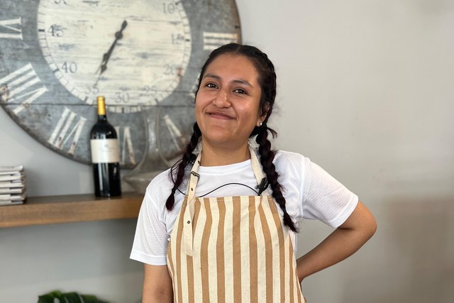 Daira Nayeli Ramos poses in uniform and an apron inside Casa Román.