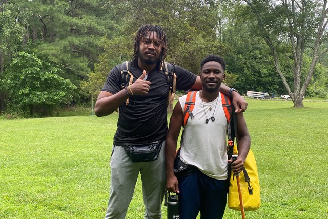 Two participants with backpacks pose among trees during Roberto Blanco’s Summer Camp experience in Missouri.